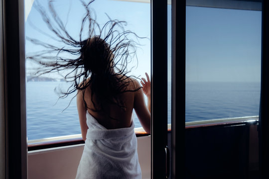 young woman looking through the window, flying hair