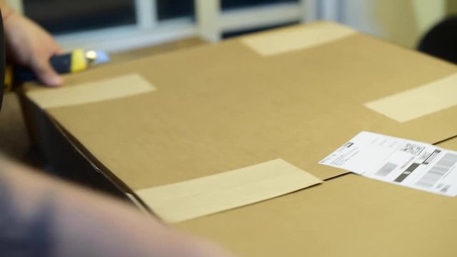 abriendo caja paquete env&iacute;o con navaja