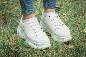 Close up female feet in sneakers on green grass in the park
