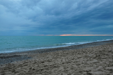 Fototapeta na wymiar Sunset against a stormy sky and blue sea
