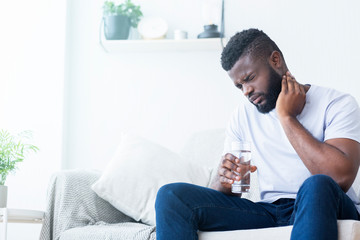 African american man suffering from neck pain at home
