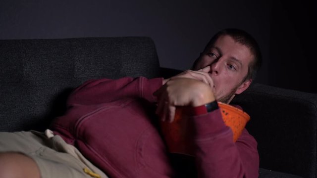 Overweight Caucasian Male Picking Nose and Eating it on a Sofa and being Lazy Watching TV