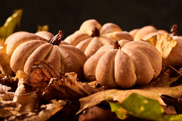 Homemade cookies in shape of pumpkin in autumn leaves. Halloween handmade cookies on a table, close up