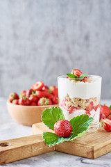 Strawberry granola or smoothie in glass and fresh berries in a wooden bowl. Healthy breakfast