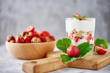 Smoothie with summer strawberry in glass jar and fresh berries  in wooden bowl on a gray background