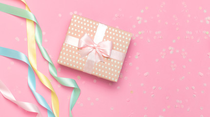 Gift or present box, beautiful festive ribbon, confetti on pink background top view. Flat lay composition for celebration, holiday, birthday Valentine's Day March 8 mother day, wedding. Congratulation