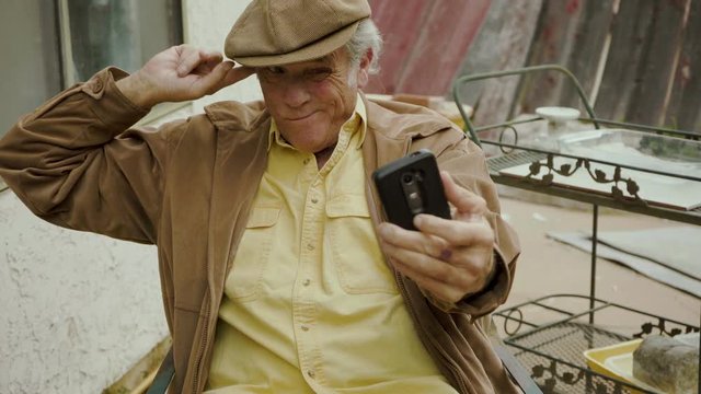 Funny old man selfie with silly facial expressions and putting finger in his ear, comical and humorous clip