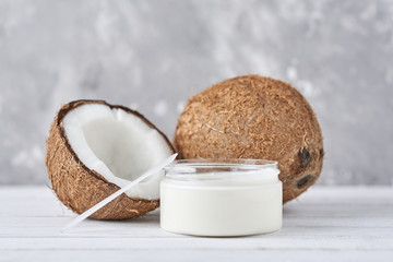 Coconut with oil in jar on a gray background