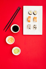 A classic philadelphia and sushi rolls with wasabi; ginger and soy sauce on white tray