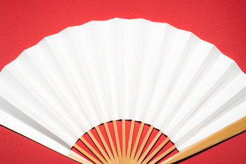 whtie Japanese foldable fan on red background with copy space