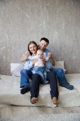 Obraz premium Happy Young Caucasian Family Sitting on Bed