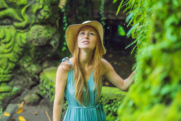 Young woman traveler in a Balinese garden overgrown with moss. Travel to Bali concept