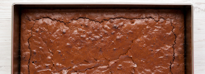 Homemade chocolate brownie on a white wooden table, overhead view. Top view, from above, flat lay. Close-up.