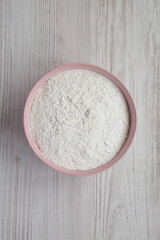 Gluten free rice flour in a pink bowl over white wooden background,  top view. Flat lay, overhead, from above.