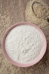 Gluten free rice flour in a pink bowl, overhead view. Flat lay, top view, from above. Close-up.