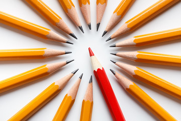 Group of classic yellow pencils surrounding red leader