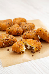 Fried camembert on a baking sheet on a white wooden background, side view. Close-up.