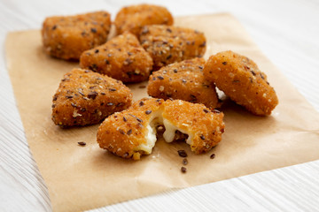 Fried camembert on a baking sheet on a white wooden background, side view. Close-up.