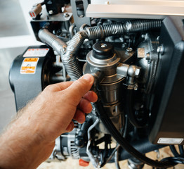Obraz premium Male hand repairing demonstrating the new 4-stroke, vertical, water-cooled diesel engine powerboat engine