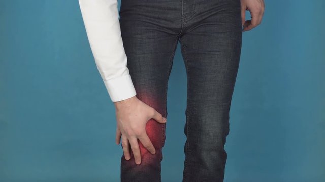 A man clings to a sore knee, pain and inflammation in the knees, the concept of bursitis and osteoarthritis, arthroplasty, biotechnology