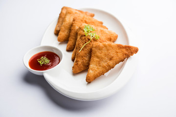 crispy Potato triangles or batata vada covered with bread crumbs and then deep fried. served with tomato ketchup. selective focus
