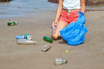 Care about nature. Young woman touris volunteer busy collecting rubbist, picks up plastic bottles, protects environment from disastrous consequences, holds garbage bag, cleaning beach from trash