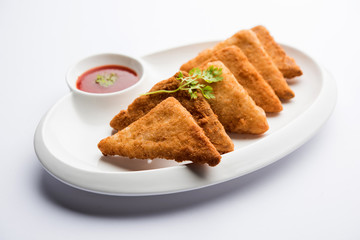 crispy Potato triangles or batata vada covered with bread crumbs and then deep fried. served with tomato ketchup. selective focus