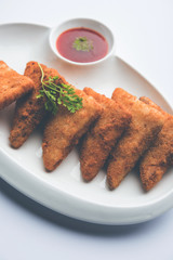 crispy Potato triangles or batata vada covered with bread crumbs and then deep fried. served with tomato ketchup. selective focus
