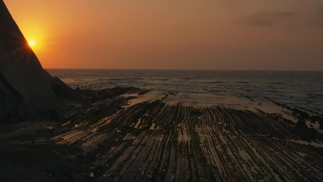 Zoom in sun hides behind mountain at sunset