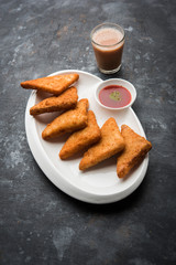crispy Potato triangles or batata vada covered with bread crumbs and then deep fried. served with tomato ketchup. selective focus