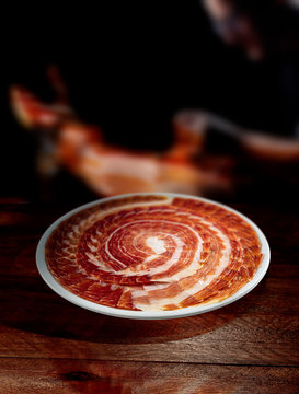 jam&oacute;n iberico cortado en plato sobre fondo de madera.  Iberian ham cut
