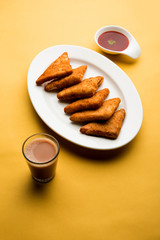 crispy Potato triangles or batata vada covered with bread crumbs and then deep fried. served with tomato ketchup. selective focus