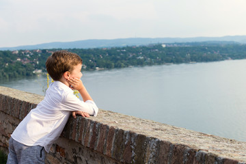 Fototapeta na wymiar Small boy enjoying the view at riverside.