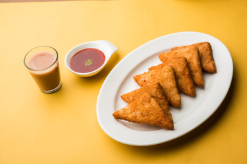 crispy Potato triangles or batata vada covered with bread crumbs and then deep fried. served with tomato ketchup. selective focus
