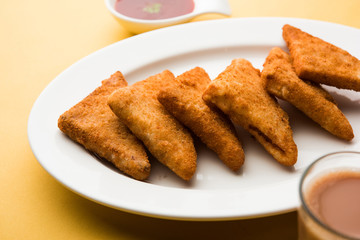 crispy Potato triangles or batata vada covered with bread crumbs and then deep fried. served with tomato ketchup. selective focus