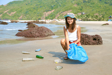 Care about nature. Young woman touris volunteer busy collecting rubbist, picks up plastic bottles,...