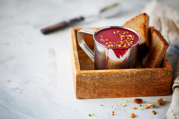 Traditional vegetarian red beet soup or smoothie decorated with pistachios in a metal mug on gray background with copy space for text. Horizontal orientation