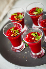Vegetarian soup or smoothies of red beets in shot glass and decorated with chopped parsley and garlic served at a banquet or party. Close-up, vertical orientation