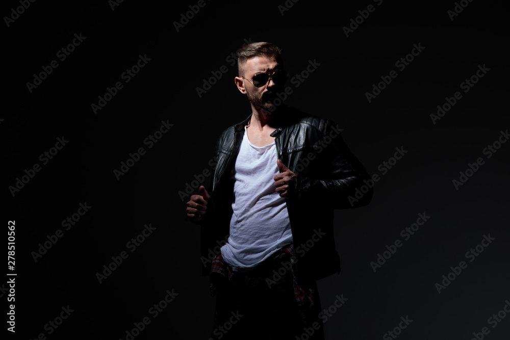 Wall mural Determined dramatic guy fixing his leather jacket