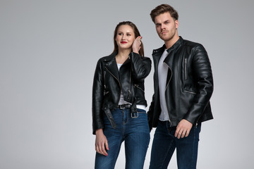 serious man in leather jacket standing near smiling woman