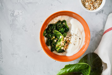 Healthy savory oatmeal with greens and yogurt high in fiber and protein in bowl on gray background top view,easy to prepare for breakfast or brunch.Healthy food,balanced diet concept.Copy space