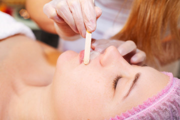 Young woman receiving facial epilation close up. Cosmetologist removes hair on face. Beauty salon, mustache depilation