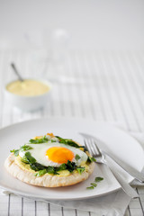 Healthy homemade breakfast or brunch (quick meal)-spiced fried eggs with Indian spices and sauteed spinach used to top toasted pitas spread with turmeric yogurt on white plate with copy space.