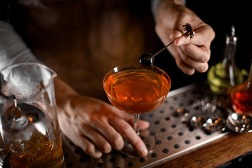 Bartender putting berry on the skewer on the cocktail glass