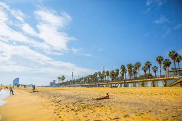 People walking on the Barcelona beach. Summer vacations travel. Barceloneta on sunny day. Tourists relaxing.