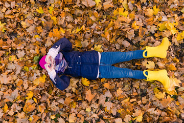 Preteen girl lay at leaves and show heart