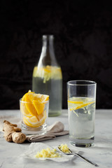 Homemade refreshing infused detox water or lemonade in glass bottles with grated ginger and lemon on dark background close-up.Healthy vegan drink summer concept.Selective focus