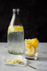 Fototapeta premium Homemade refreshing infused detox water or lemonade in glass bottles with grated ginger and lemon on dark background close-up with copy space for text.Healthy vegan drink concept.Selective focus