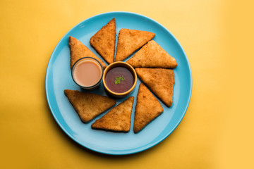 crispy Potato triangles or batata vada covered with bread crumbs and then deep fried. served with tomato ketchup. selective focus