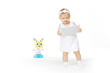 little girl all in white with tablet and toy